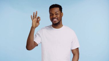 Beyaz tişörtlü mutlu Afro-Amerikalı adam mavi üzerinde 