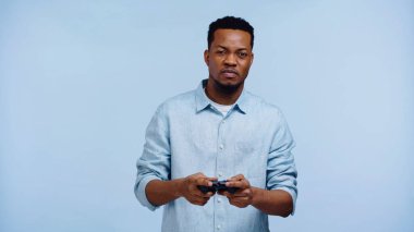 KYIV, UKRAINE - 22, 2019: mavi üzerinde izole edilmiş video oyunu oynayan Afrikalı Amerikalı adam 