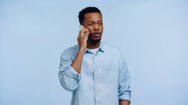 Gömlekli Afro-Amerikan bir adam cep telefonuyla konuşuyor.