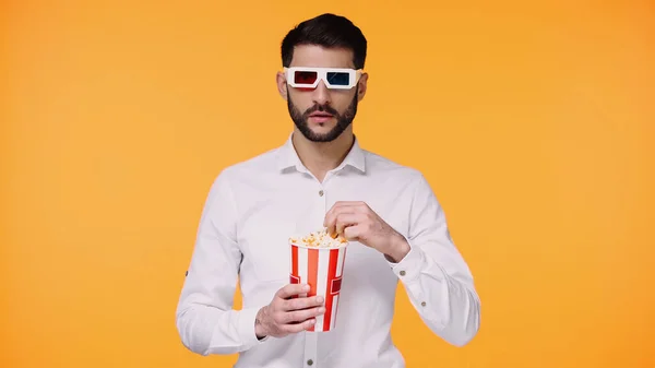 戴3D眼镜的大胡子男人拿着装有爆米花的桶 用黄色隔离 — 图库照片
