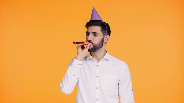 bearded man in white shirt blowing in party horn isolated on yellow