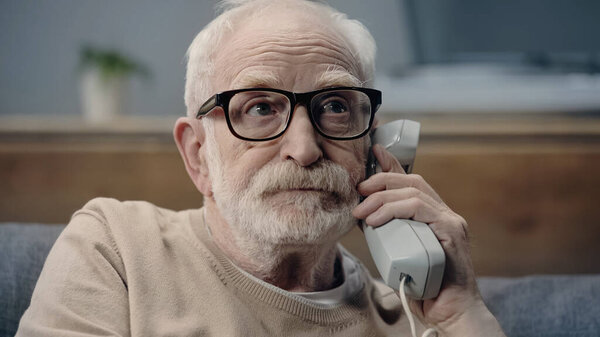 Senior man with dementia holding handset of vintage telephone 