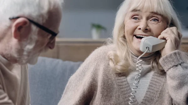 Szczęśliwa Seniorka Demencją Rozmawiająca Przez Telefon Przy Mężu — Zdjęcie stockowe