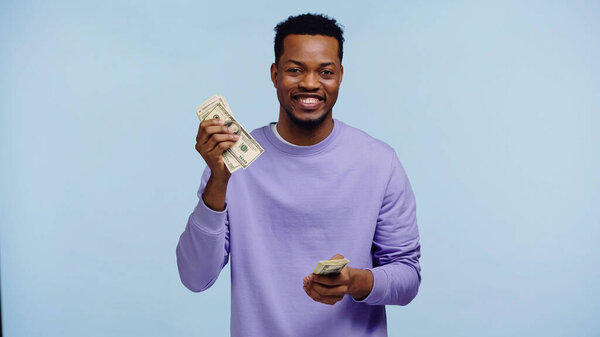 happy african american man holding money isolated on blue