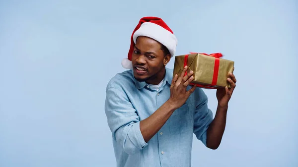 Nieuwsgierig Afrikaans Amerikaanse Man Santa Hoed Schudden Kerst Gift Box — Stockfoto