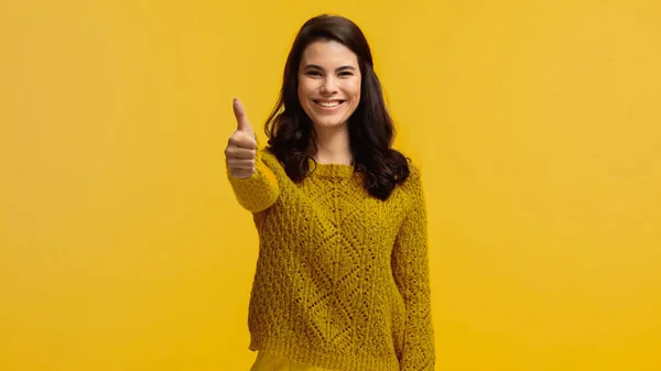 穿着毛衣的年轻而快乐的女人在黄色的衣服上露出大拇指 — 图库照片