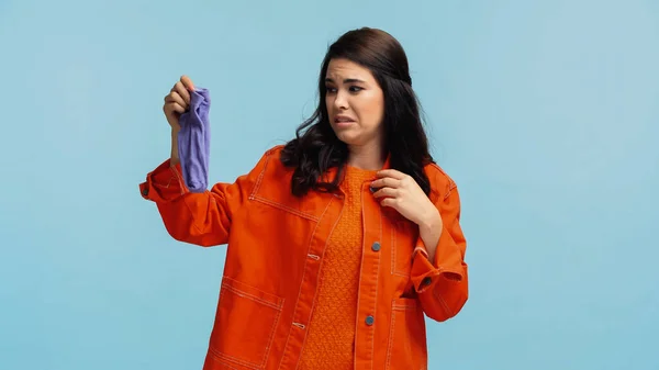 穿着橙色斜纹棉布夹克的年轻而厌恶的女人 穿着蓝色孤立的臭袜子 — 图库照片