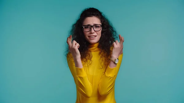 Jeune femme en lunettes aux doigts croisés isolé sur bleu — Photo de stock