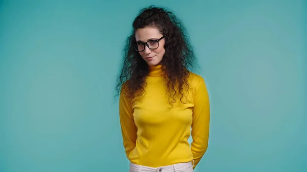 Сором'язлива молода жінка в окулярах стоїть ізольовано на синьому — стокове фото