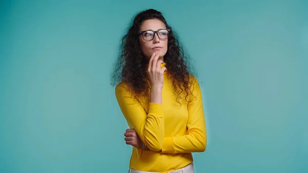 Nachdenkliche junge Frau mit Brille schaut vereinzelt auf blauem Grund weg — Stockfoto
