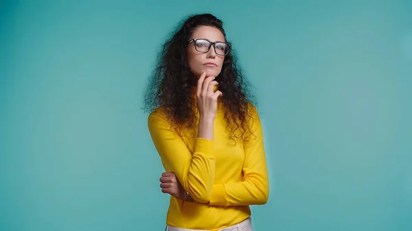 Mujer reflexiva en gafas mirando hacia otro lado aislado en azul - foto de stock