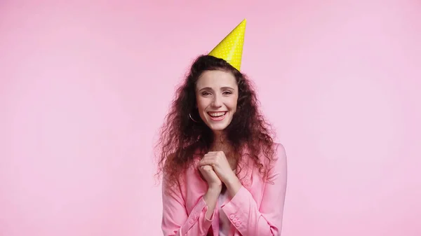 Jeune femme souriante en bonnet de fête pendant l'anniversaire isolé sur rose — Photo de stock