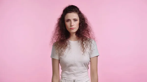 Traurige junge Frau blickt isoliert auf rosa Kamera — Stockfoto