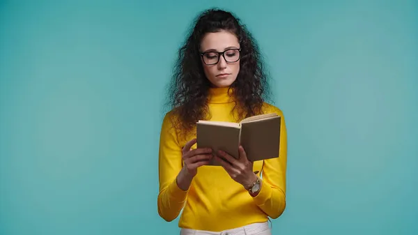 Mujer enfocada lectura libro aislado en azul - foto de stock