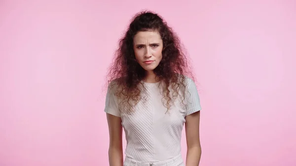 Unzufriedene junge Frau blickt isoliert auf rosa Kamera — Stockfoto