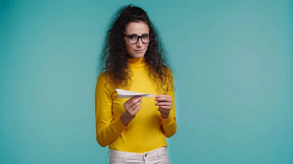 Smiling young woman holding paper plane isolated on blue — Stock Photo