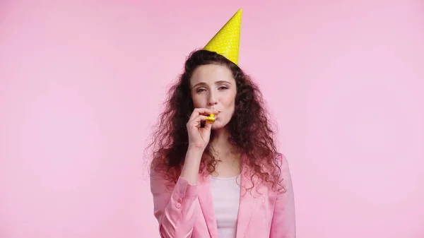 Joven mujer soplando en partido cuerno aislado en rosa - foto de stock