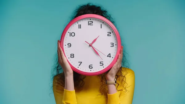 Femme visage obscurcissant avec horloge murale isolé sur bleu — Photo de stock