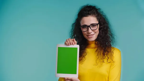 Femme positive dans des lunettes tenant tablette numérique avec écran vert isolé sur bleu — Photo de stock