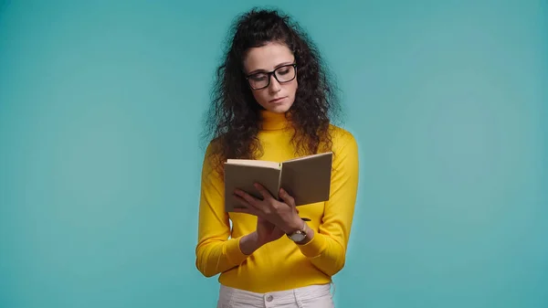 Jeune et ciblée femme lecture livre isolé sur bleu — Photo de stock