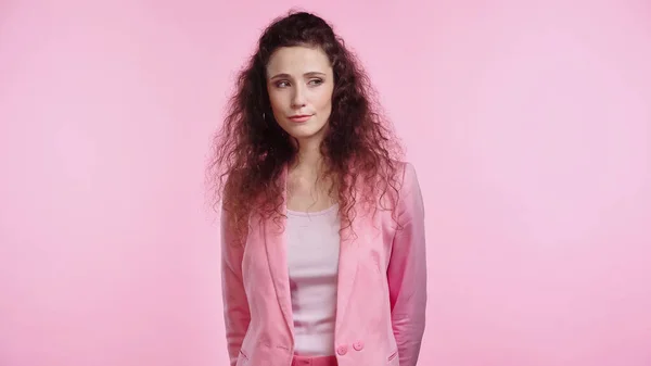 Brunette and curly young woman looking away isolated on pink — Stock Photo