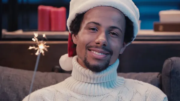 Afrikanisch-amerikanischer Mann mit Weihnachtsmütze und Wunderkerze — Stockfoto