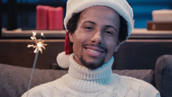 African american man in santa hat holding sparkler — Stock Photo