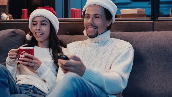 Довольные африканский американец и женщина смотрят фильм на Рождество — стоковое фото