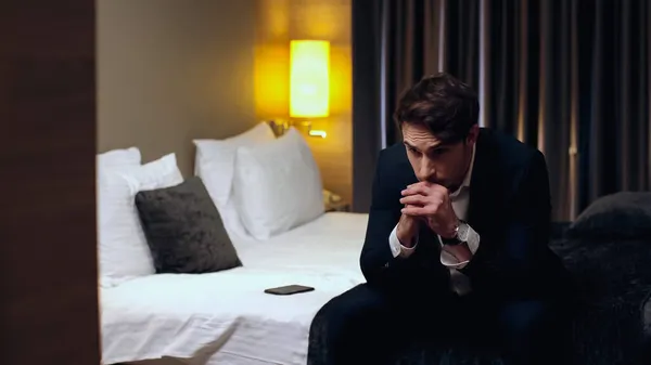 Беспокойный бизнесмен сидит с сжатыми руками в гостиничном номере — стоковое фото