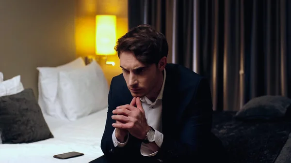 Pensive businessman sitting on bed in hotel room — Stock Photo