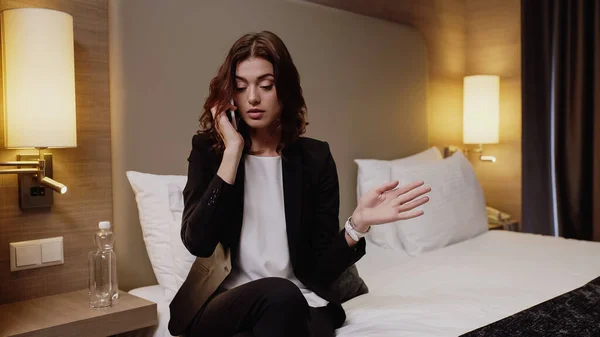 Tätowierte und unzufriedene Geschäftsfrau spricht auf Smartphone im Hotelzimmer — Stockfoto