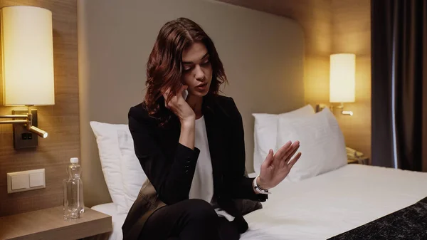 Татуйована бізнес-леді жестикулює під час розмови на смартфоні в готельному номері — стокове фото