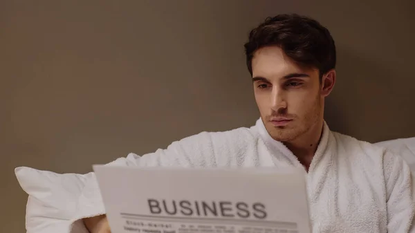 Homem focado lendo jornal de negócios enquanto descansa no quarto de hotel — Fotografia de Stock