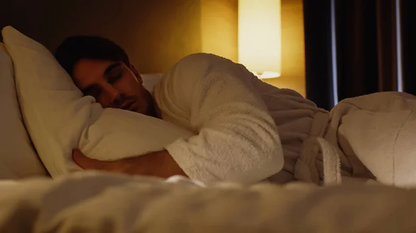 Surface level of young man sleeping on bed in hotel room — Stock Photo