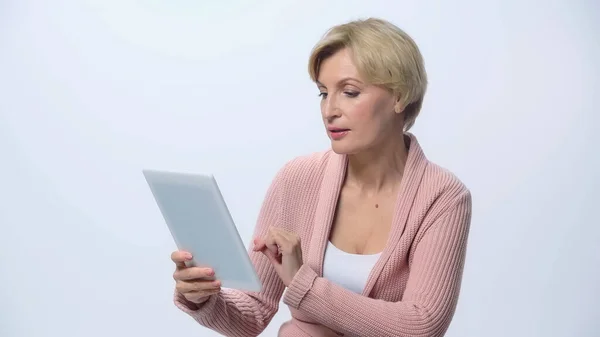 Femme blonde mature utilisant une tablette numérique isolée sur blanc — Photo de stock