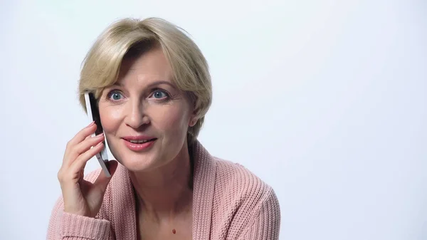 Здивована і усміхнена жінка середнього віку розмовляє на смартфоні ізольовано на білому — Stock Photo