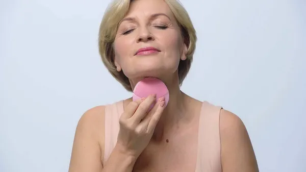 Mujer madura usando limpiador de silicona con los ojos cerrados aislados en blanco — Stock Photo