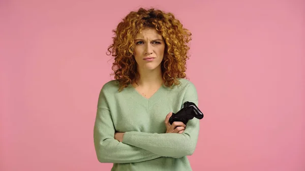 KYIV, UKRAINE - DECEMBER 22, 2021: upset woman with joystick standing with crossed arms isolated on pink — Foto stock