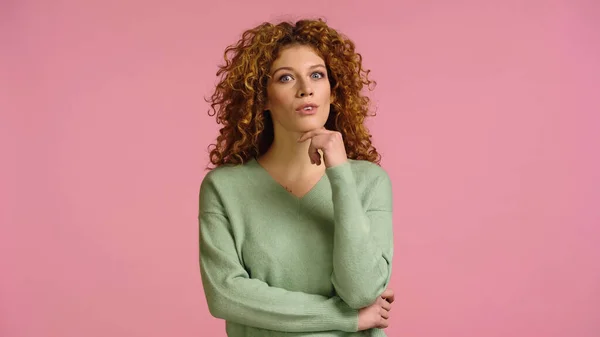Surprised woman with curly hair holding hand near face and looking at camera isolated on pink — Stock Photo