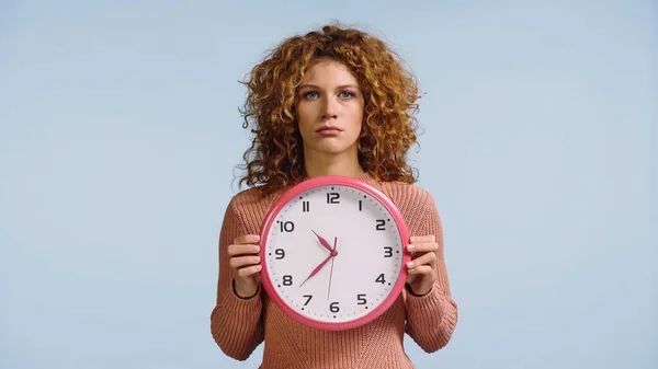 Mujer molesta con reloj redondo mirando a la cámara aislada en azul - foto de stock