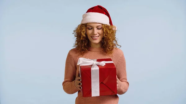 Felice rossa donna in cappello di Babbo Natale guardando il nuovo anno presente isolato su blu — Foto stock