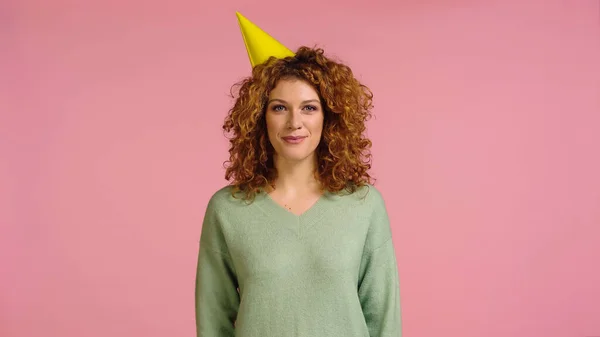 Rousse gaie et femme bouclée en chapeau de fête en regardant la caméra isolée sur rose — Photo de stock