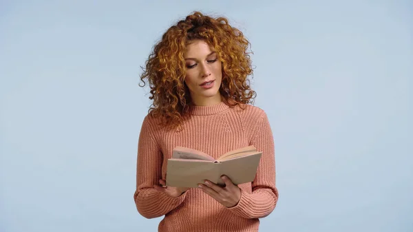 Femme concentrée avec des cheveux rouges livre de lecture isolé sur bleu — Photo de stock