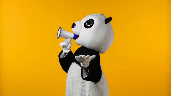 Person in panda bear costume talking in megaphone isolated on yellow — Stock Photo