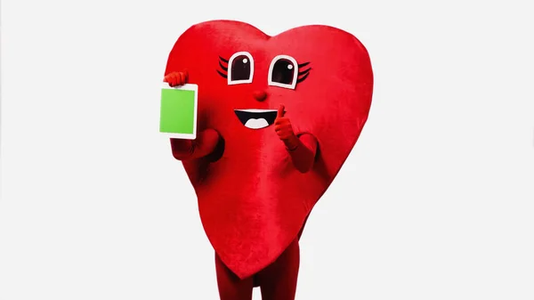 Person in red heart costume holding digital tablet with green screen and showing thumb up isolated on white — Stockfoto