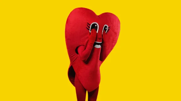 Sad person in heart costume touching cartoon eyes while imitating crying isolated on yellow — Fotografia de Stock