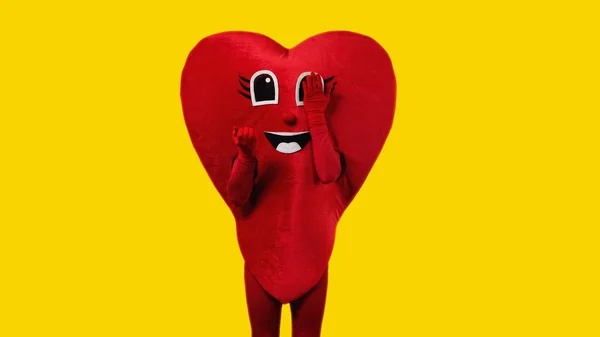 Persona in costume cuore toccando occhio cartone animato isolato su giallo — Foto stock