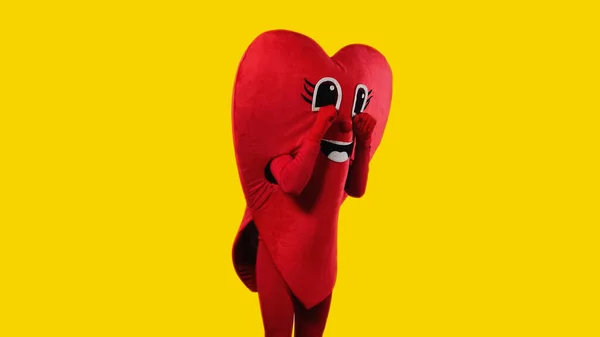 Person in heart costume touching cartoon eyes while imitating crying isolated on yellow — Stock Photo