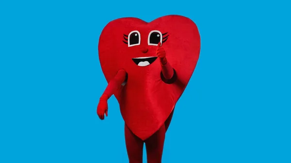 Persona in costume cuore positivo mostrando come isolato sul blu — Foto stock