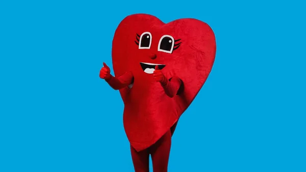 Person in joyful heart costume showing thumbs up isolated on blue — Foto stock